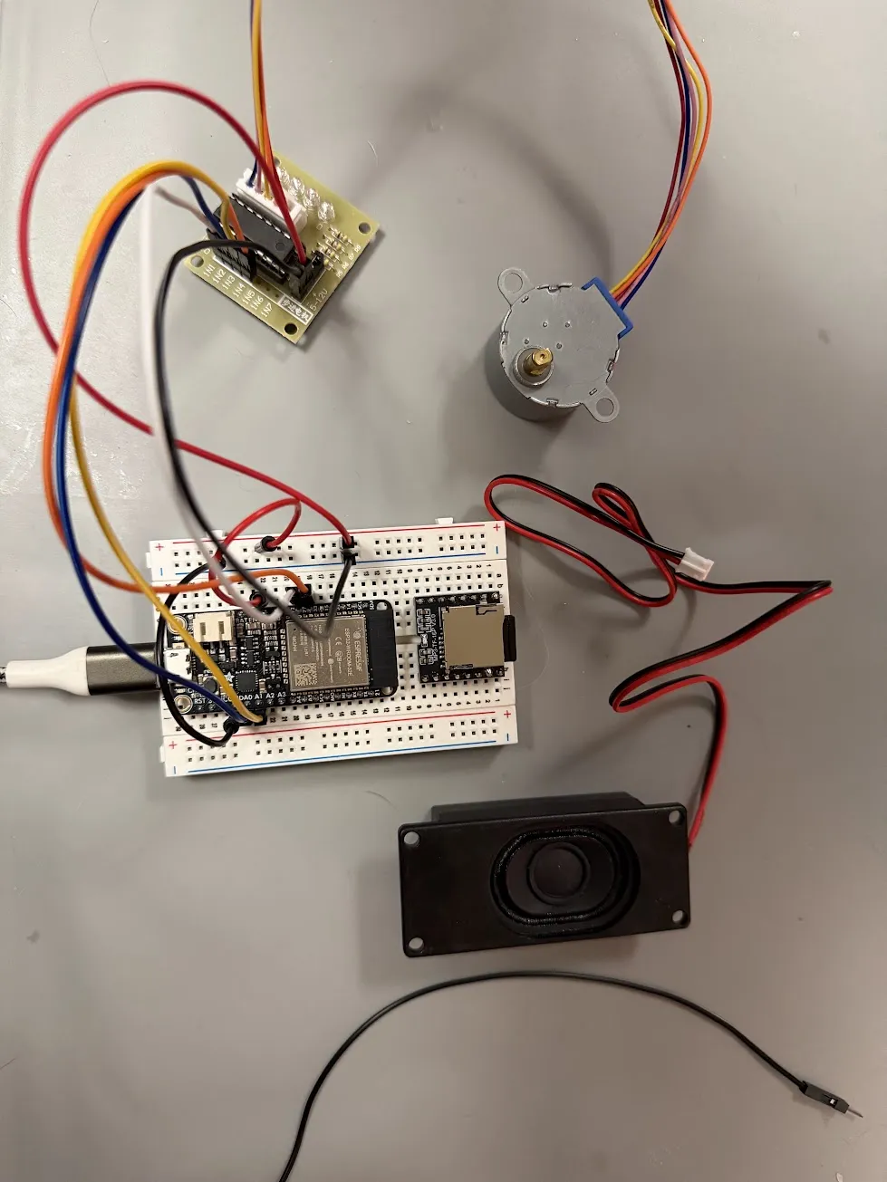 ESP32, DFPlayer Mini, stepper motor, and speaker wired up on a breadboard