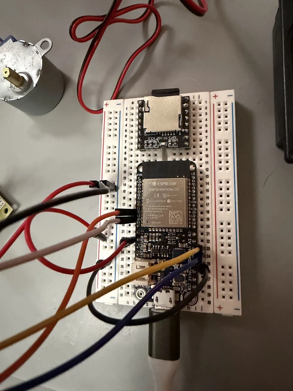 Close-up of the ESP32 HUZZAH32 on a breadboard with the DFPlayer Mini module and SD card visible behind it