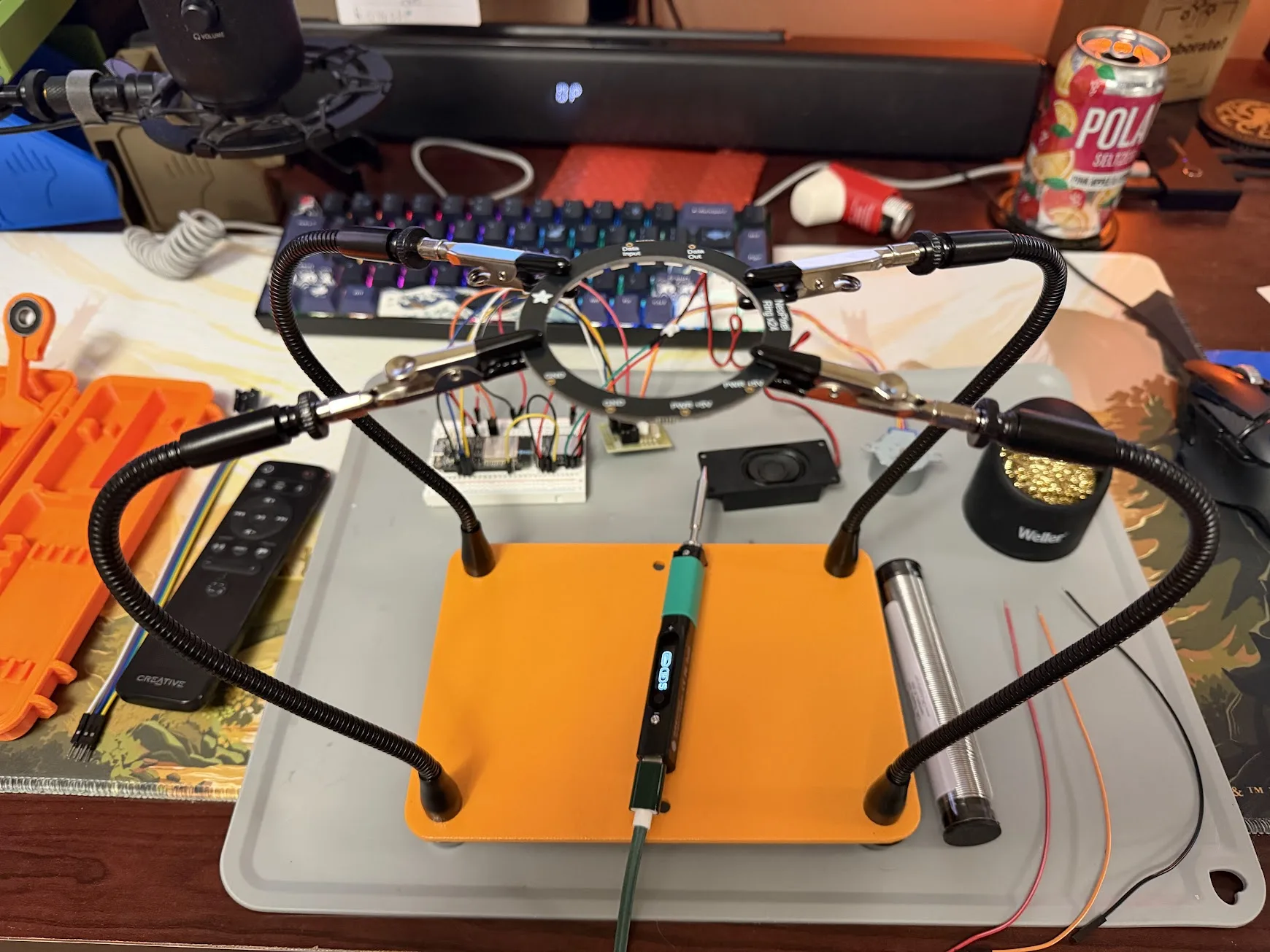 Full soldering workstation: four-arm helping hands, Pinecil V2 iron on the mat, Weller tip cleaner, and the ESP32 breadboard assembly in the background