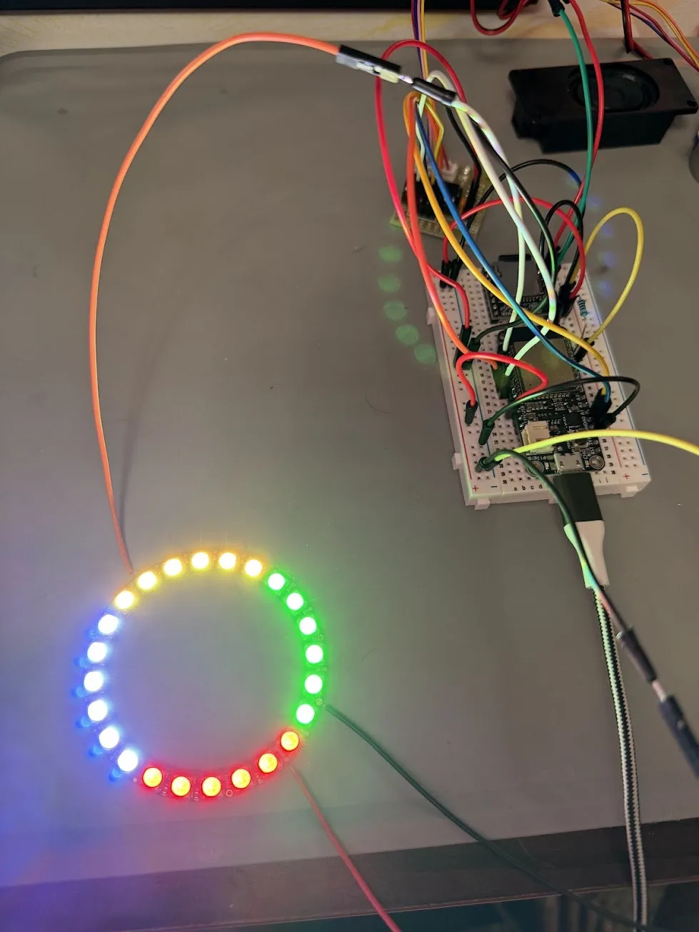 NeoPixel ring fully lit with all 24 pixels glowing in rainbow colors, connected to the ESP32 breadboard by three jumper wires