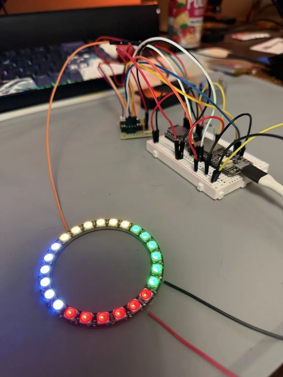 NeoPixel ring glowing with four gem color quadrants — topaz yellow, emerald green, ruby red, diamond blue-white